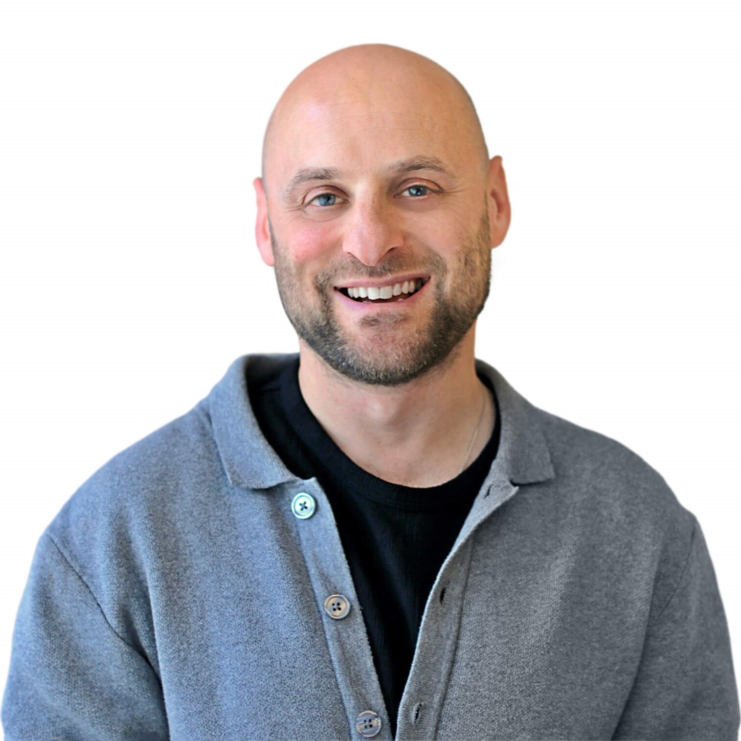 A bald man wearing a gray sweater smiles warmly at the camera.