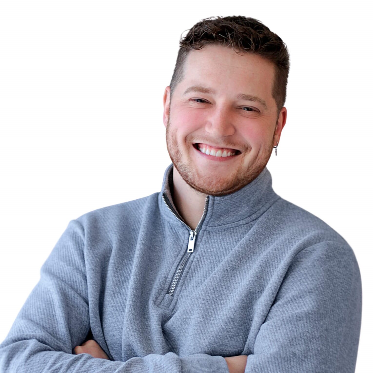 A man wearing a gray sweater smiles warmly at the camera.