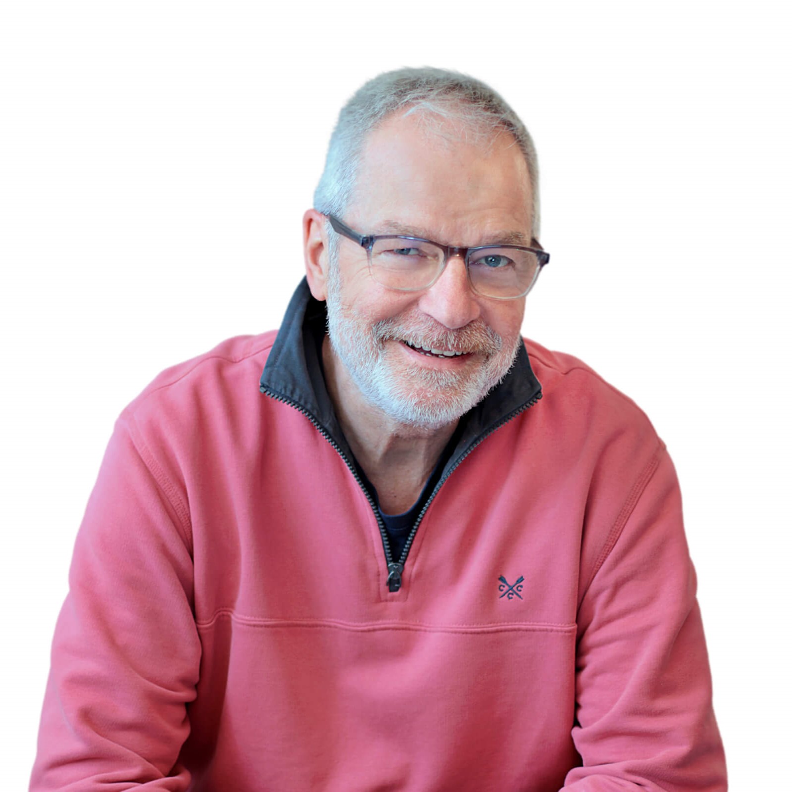A man in a pink sweater and glasses sits comfortably, exuding a casual and approachable demeanor