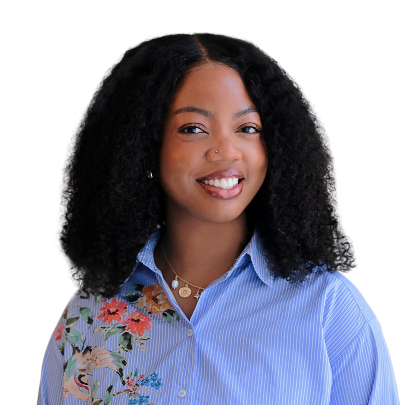 A woman with curly hair wearing a blue shirt smiles at the camera.