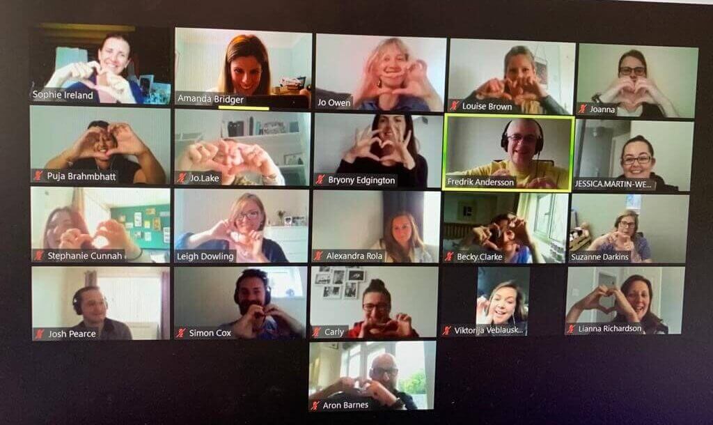 A group of people forming a heart shape with their hands, displayed on a computer screen.